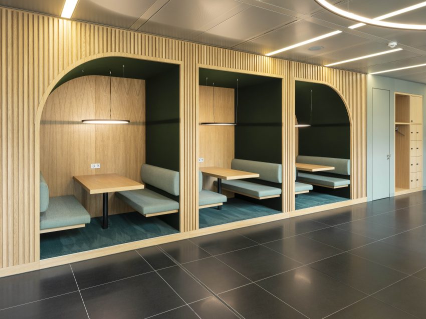 Drei Nischen mit Holzwänden, gepolsterten Sitzbänken und Tischen, beleuchtet durch hängende Lampen in modernem Innenraum